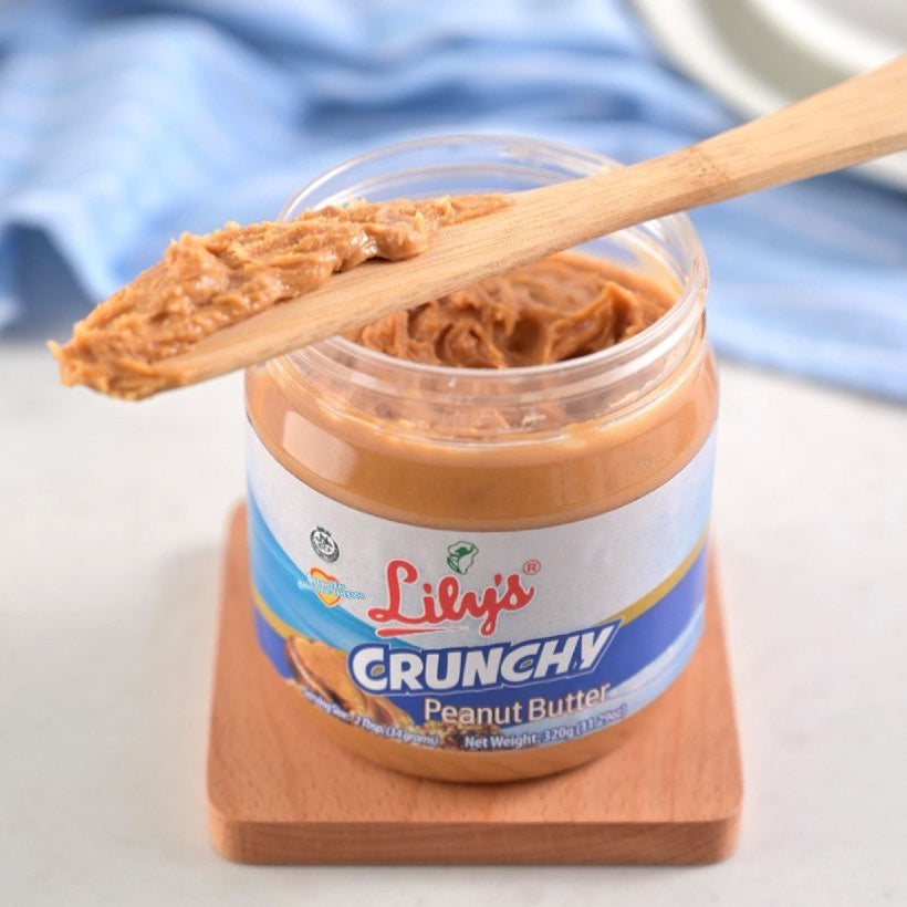 Jar of Lily's Crunchy Peanut Butter with a wooden spoon on a white surface.