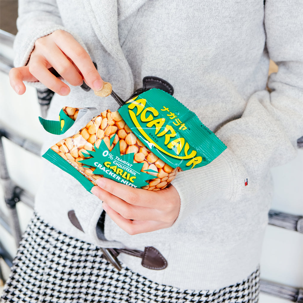 Person holding a package of Nagaraya Garlic Cracker Nuts with a blurred background